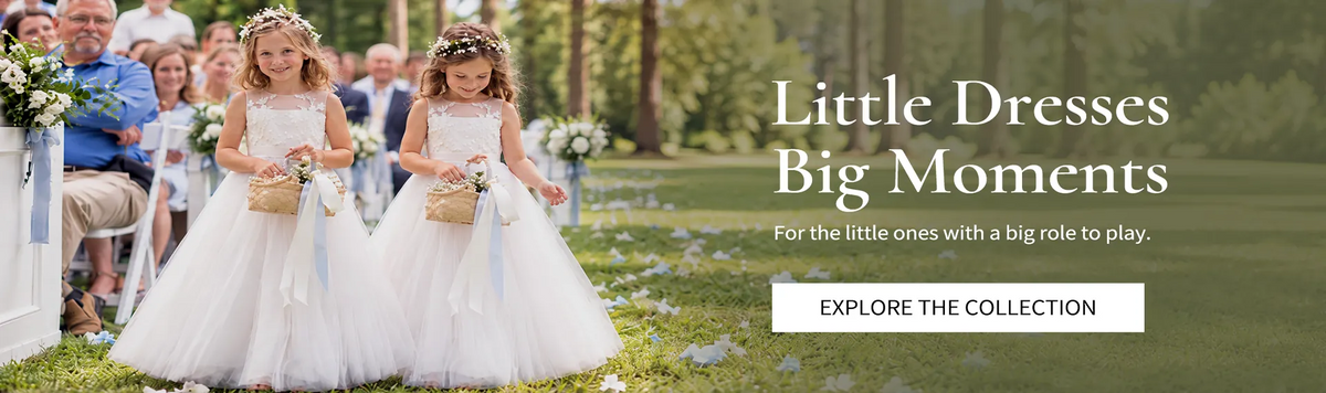 Two flower girls in white tulle dresses walking down the aisle at an outdoor wedding